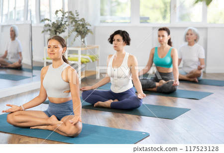 Young woman doing yoga in group in studio 117523128