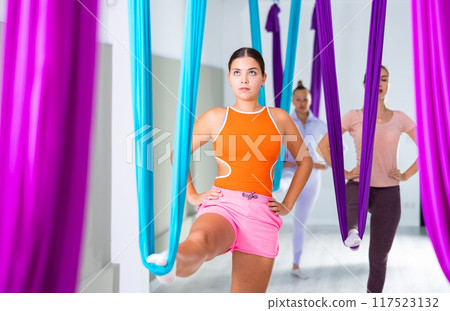 Young yoga woman doing aerial yoga practice in hammock in fitness club Young yoga woman doing aerial yoga practice in hammock in fitness club 117523132