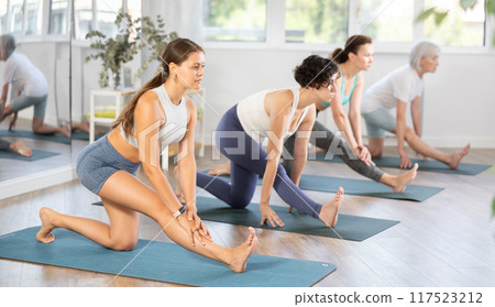 Girl performing Ardha Hanumanasana stretching asana at yoga class 117523212