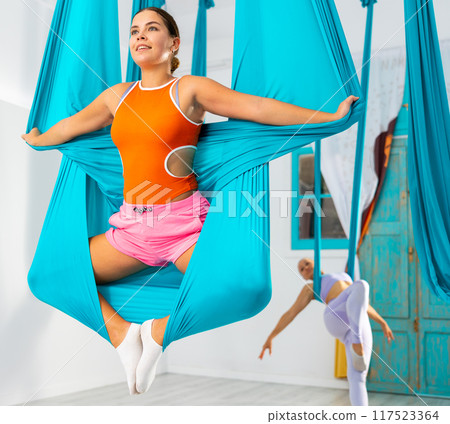 Young women making antigravity yoga exercises with group of people Young women making antigravity yoga exercises with group of people 117523364