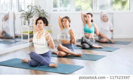 Adult woman doing pilates in group in studio Adult woman doing pilates in group in studio 117523397