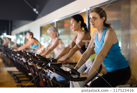 Elderly woman warming up on bike at gym Elderly woman warming up on bike at gym 117523416