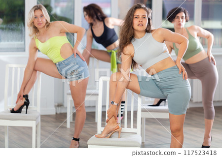 Group of women in high heels rehearsing dance with their feet on chair Group of women in high heels rehearsing dance with their feet on chair 117523418