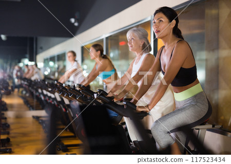 Woman on stationary bike workout in gym 117523434