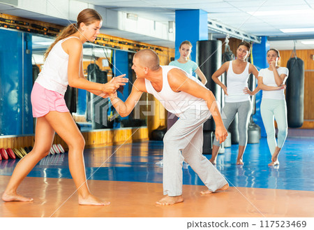 Young woman practicing supinating wristlock with man in self-defense course Young woman practicing supinating wristlock with man in self-defense course 117523469