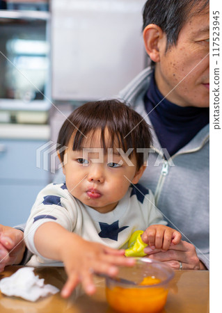 Toddler and grandfather eating dessert Toddler and grandfather eating dessert 117523945