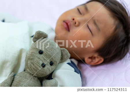 一個 2 歲幼兒抱著毛絨襪子玩具睡覺的睡臉特寫 一個 2 歲幼兒抱著毛絨襪子玩具睡覺的睡臉特寫 117524311