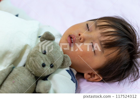 一個 2 歲幼兒抱著毛絨襪子玩具睡覺的睡臉特寫 一個 2 歲幼兒抱著毛絨襪子玩具睡覺的睡臉特寫 117524312
