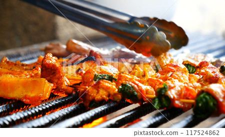 BBQ Barbecue grilled meat stick on fire flame with hot charcoal cooking outside. Beef grilling picnic outdoor with smoke bacon spicy sausage for party. Grill pork bbq on fire flame 117524862