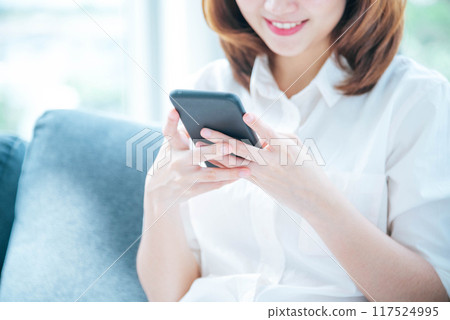Asian woman holding smartphone with E-commerce Shopping online website Reading Online Article, Blog, vlog. Young Woman hands holding phone technology lifestyle. Happy Woman using digital smart phone 117524995
