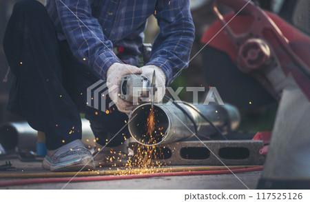 Construction Worker hands using Welding machinery iron metal sparking. Men hands wear protective glove Hot flame metal work cutting fire iron workshop. Locksmith use Welding machine cut metal process 117525126