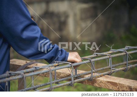 Men hands using pincer pliers iron wire reinforcement of concrete work. Construction Worker hands bending cutting steel wire fences bar. Outdoor Worker using wire bending pliers, construction work. 117525133