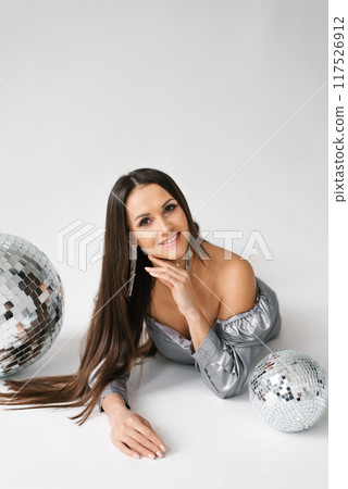 Smiling woman is laying on the ground with a silver ball and a silver ball Smiling woman is laying on the ground with a silver ball and a silver ball 117526912