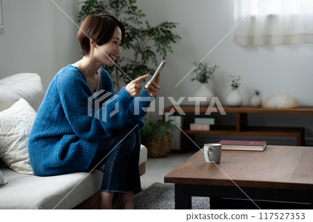 Middle-aged woman using a smartphone in the living room 117527353