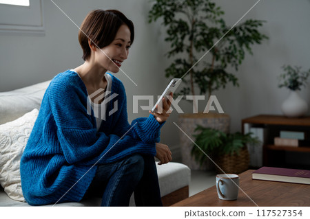 Middle-aged woman using a smartphone in the living room 117527354