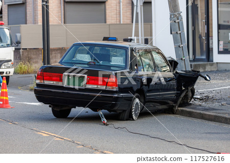 A car crashed into a utility pole, causing extensive damage to the front end, and the pole leaning forward 117527616