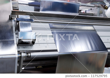 aluminum foil for food packaging on automatic packing machine in food product factory. industrial and technology concept. aluminum foil for food packaging on automatic packing machine in food product factory. industrial and technology concept. 117529795