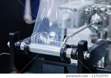 roll of plastic packaging film on the automatic packing machine in food product factory. industrial and technology concept. 117529797