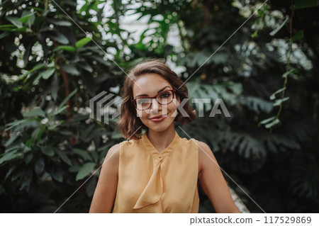 Beautiful woman standing in botanical garden, in the middle of lush green foliage. Beautiful woman standing in botanical garden, in the middle of lush green foliage. 117529869