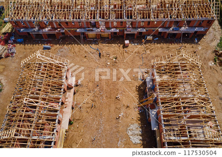 New house under construction, wooden truss system forming roof. Process of building project. New house under construction, wooden truss system forming roof. Process of building project. 117530504