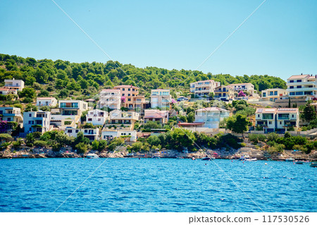 Seaside town with colorful coastal houses on hillside with boats docked along clear blue waters. Residential apartments for summer vacation on Adriatic Sea in Rogoznica, Croatia 117530526