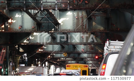 Elevated subway above New York city street. Yellow School Bus. Metropolitan over road, Queens metro. 117530977