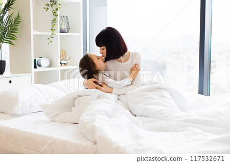 Mother and daughter hugging in cozy bed at home morning Mother and daughter hugging in cozy bed at home morning 117532671