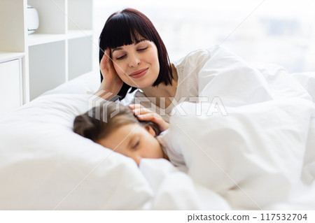 Mother and child laying in bed having a peaceful morning Mother and child laying in bed having a peaceful morning 117532704