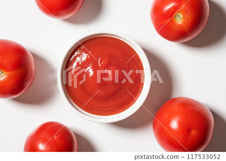 Bowl of ketchup and tomatoes on white background, top view. Portion of tomato sauce 117533052