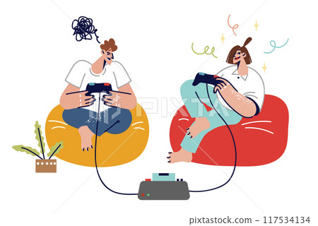 Teenagers play video games using joysticks and set-top box, sitting in soft chairs in living room 117534134