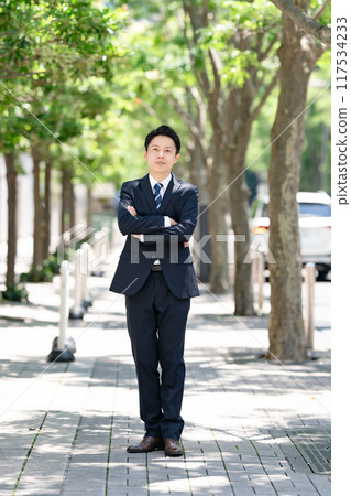 Businessman standing on a tree-lined street 117534233