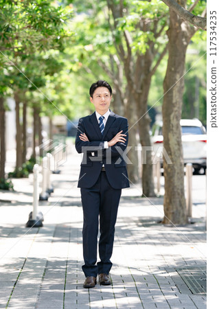 Businessman standing on a tree-lined street 117534235