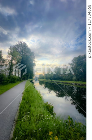 A Serene Pathway That Runs Along a Calm River with Stunning Scenic Reflections All Around A Serene Pathway That Runs Along a Calm River with Stunning Scenic Reflections All Around 117534659