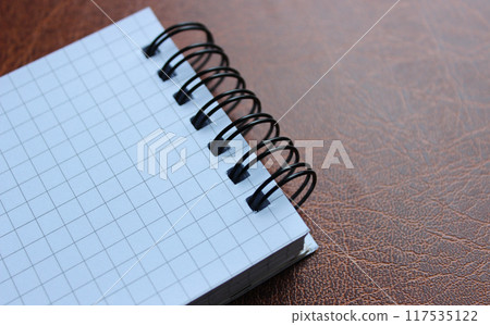 Unopened spiral notebook on leather table stock photo for title or business logo Unopened spiral notebook on leather table stock photo for title or business logo 117535122