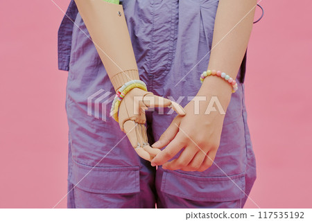 Closeup shot of hands of unrecognizable girl with disability wearing arm prosthesis, pink background 117535192