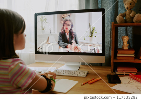 Modern teen girl with disability sitting at desk in her room listening to teacher during online lesson 117535282