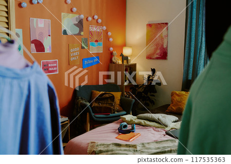 No people shot of part of modern teenagers bedroom interior with comfortable bed, colorful posters and lights on orange wall, copy space No people shot of part of modern teenagers bedroom interior with comfortable bed, colorful posters and lights on orange wall, copy space 117535363