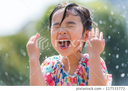 A girl splashing around in the fountain in a summer square A girl splashing around in the fountain in a summer square 117535772