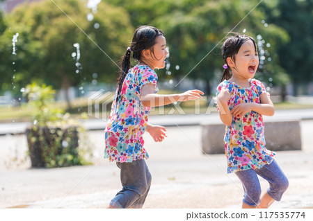 A girl splashing around in the fountain in a summer square 117535774