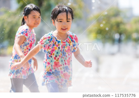 A girl splashing around in the fountain in a summer square A girl splashing around in the fountain in a summer square 117535776
