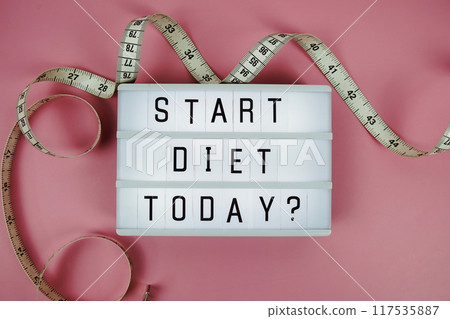 Start diet today? letterboard text on LED Lightbox and Measuring tape on pink background, Healthcare concept Start diet today? letterboard text on LED Lightbox and Measuring tape on pink background, Healthcare concept 117535887