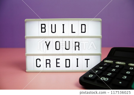 Build Your Credit letterboard text on LED Lightbox and calculator on pink and purple background 117536025