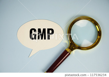 GMP text on speech bluble with magnifying glass top view on blue background GMP text on speech bluble with magnifying glass top view on blue background 117536234