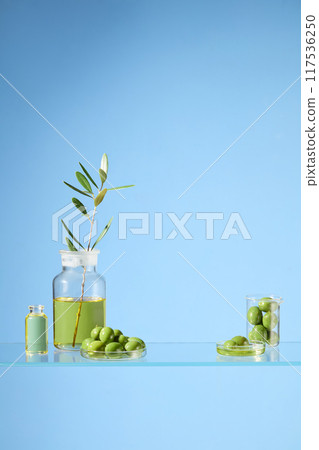 Creative photo shoot for advertising olive products, beneficial for health and beauty. The photo was taken with a laboratory layout, glassware containing fresh olives is placed on a glass surface Creative photo shoot for advertising olive products, beneficial for health and beauty. The photo was taken with a laboratory layout, glassware containing fresh olives is placed on a glass surface 117536250