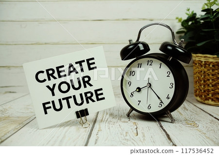 Create Your Future text on paper card with alarm clock on wooden background 117536452