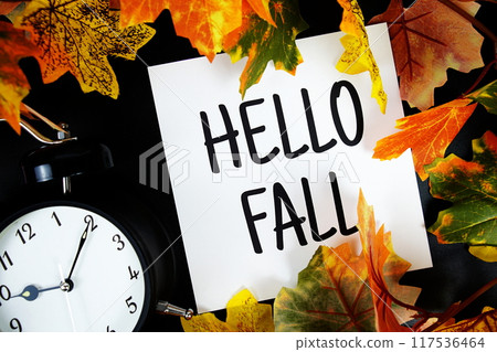 Hello Fall text with alarm clock and maple leaf decoration on wooden background Hello Fall text with alarm clock and maple leaf decoration on wooden background 117536464