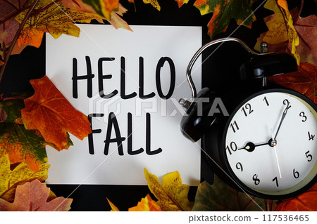 Hello Fall text with alarm clock and maple leaf decoration on wooden background Hello Fall text with alarm clock and maple leaf decoration on wooden background 117536465