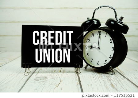 Credit Union text on paper card with alarm clock on wooden background Credit Union text on paper card with alarm clock on wooden background 117536521