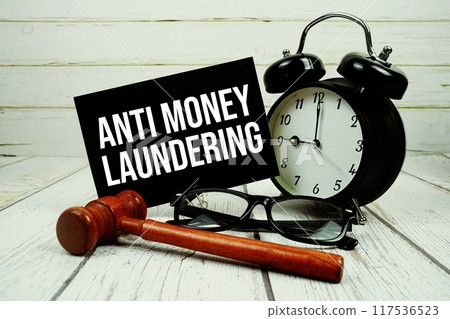 Anti Money Laundering text on paper card with alarm clock and wooden judge gavel on wooden background 117536523