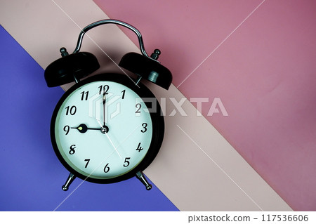 Alarm clock top view on purple and pink geometric background 117536606